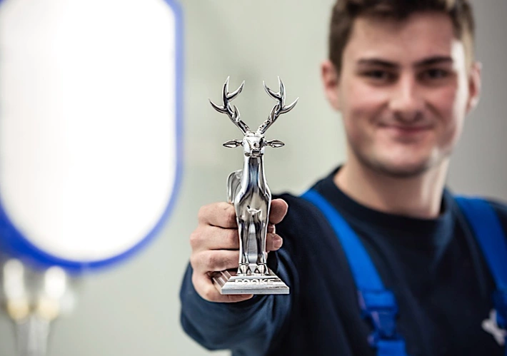 Ein Azubi hält einen Pokal in der Hand