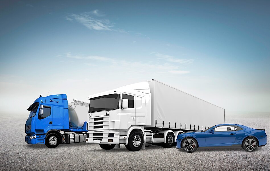 Zwei LKWs und ein blaues Auto stehen auf einem Gelände