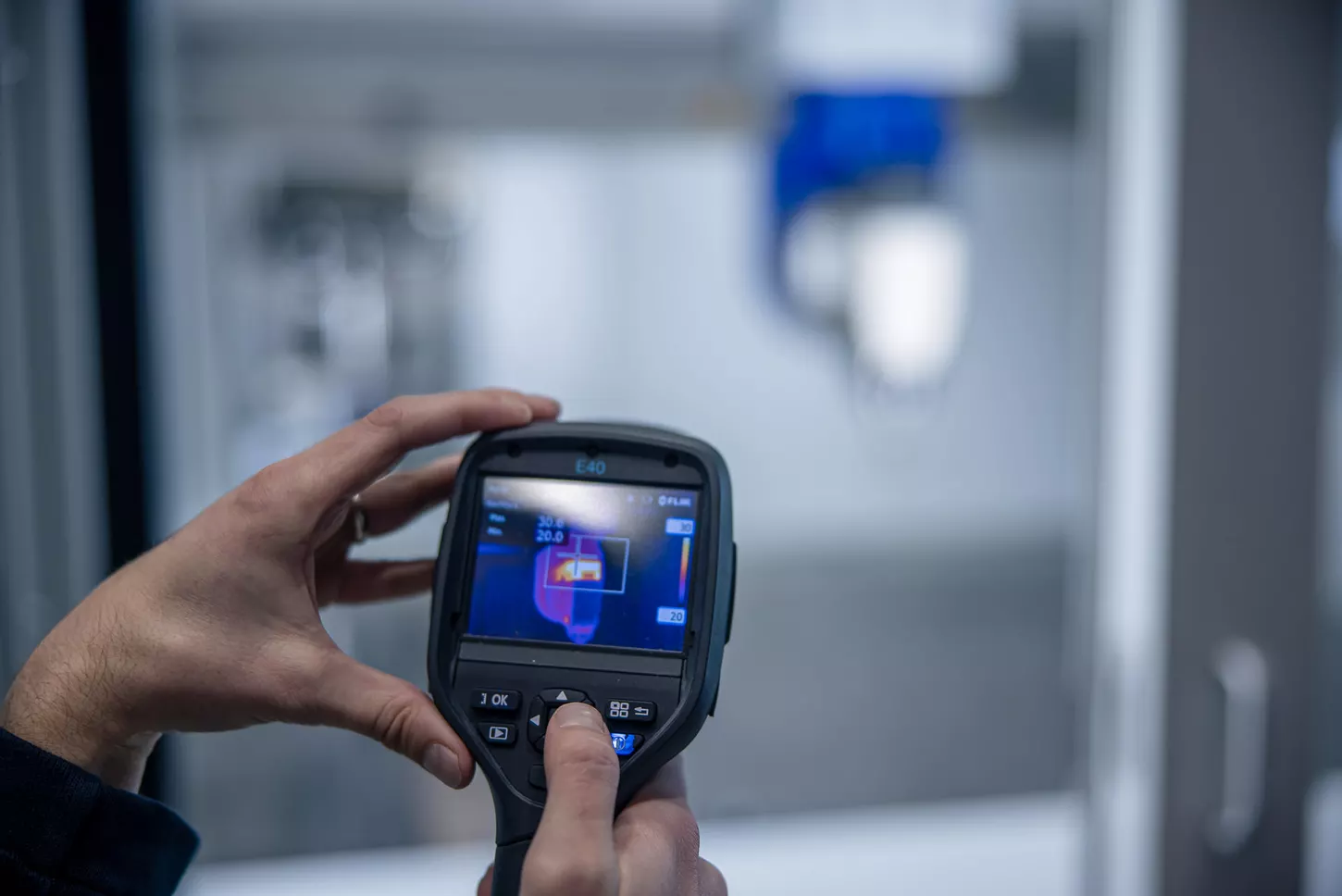 Zwei Hände halten ein digitales Messgerät in den Händen.